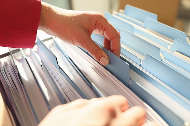 Руки женщины берут папки с необходимыми рабочими материалами в офисе