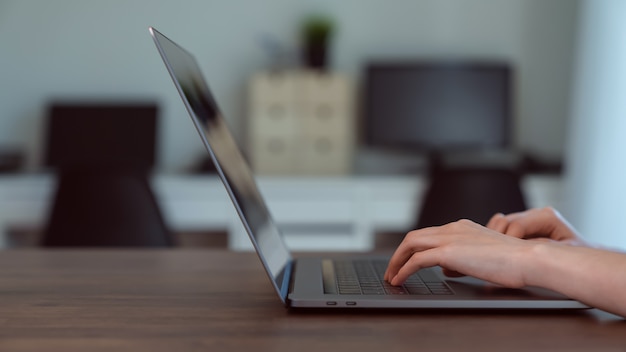 The hands of a woman typing keyboard on laptop with working online at home office.