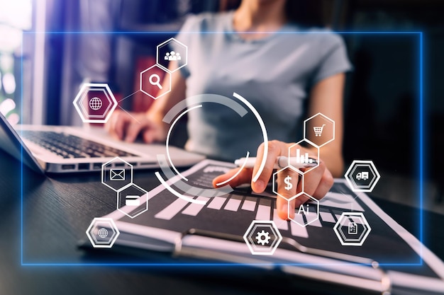 Hands of woman using mobile phone in modern office with laptop and digital tablet computer with VR icon diagram at office in morning light