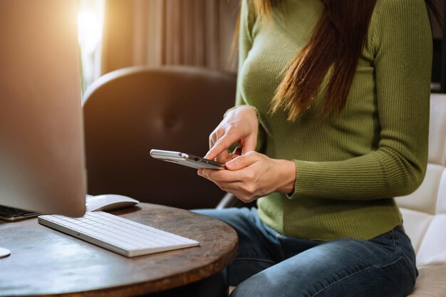 Hands of woman using mobile phone in modern office with laptop and digital tablet at home office