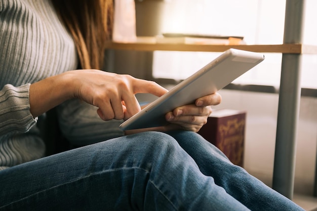 Foto mani di donna che utilizzano il telefono cellulare in un ufficio moderno con laptop e tablet digitale