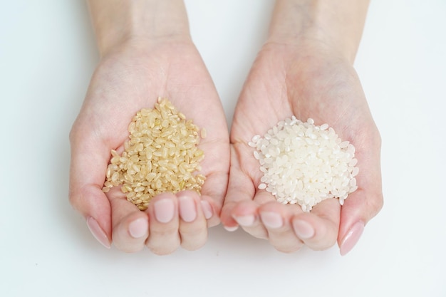 Hands of a woman with white rice and brown rice