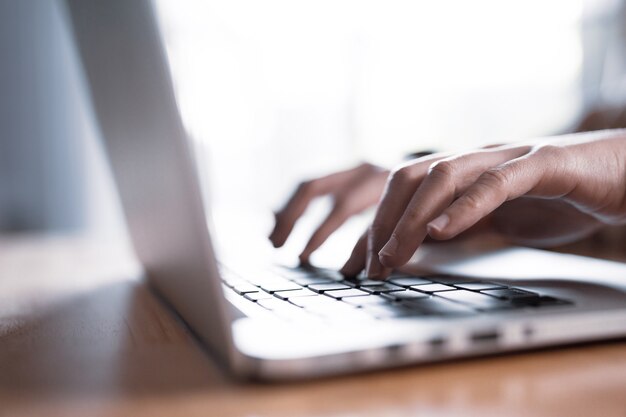 Hands of a woman working and touching on laptop touchpad on wooden table