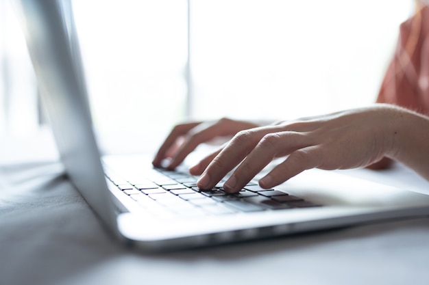 Mani di una donna che lavora e tocca il touchpad del laptop