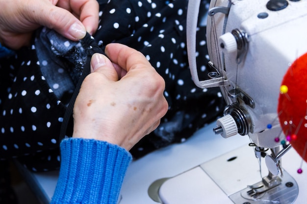 Hands work a sewing machine.