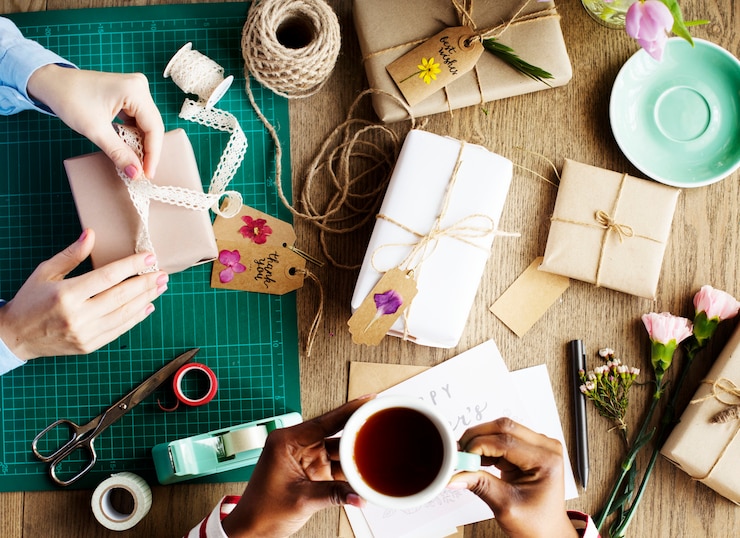 Photo hands wrapping present box with flower decoration handicraft