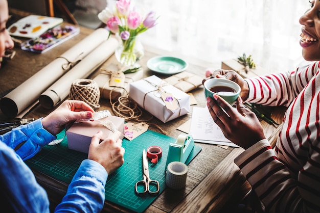 Mani che avvolgono scatola regalo con decorazione floreale