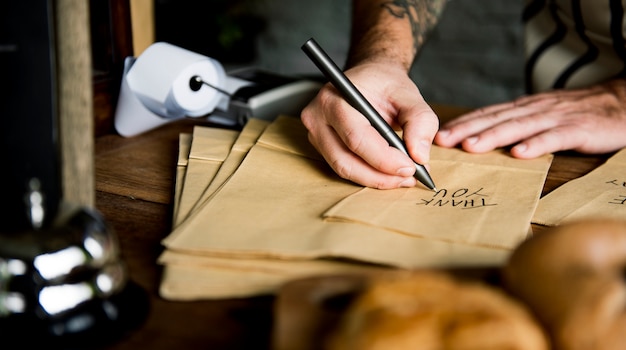 Hands writing thank you on paper bag