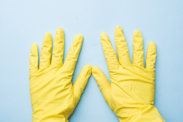 Photo hands in yellow gloves for cleaning on blue background.