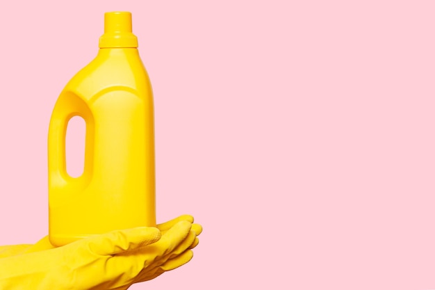 Photo hands in yellow gloves hold a yellow bottle of cleaning agent household chemicals for washing