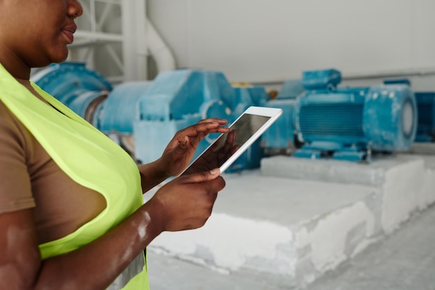 태블릿을 사용하는 공장의 젊은 아프리카계 미국인 여성 노동자의 손