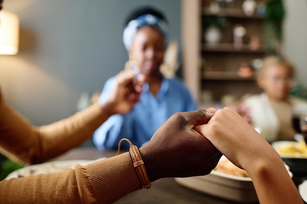 Photo hands of young african american man and his daughter during pray by festive table