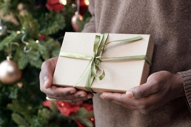 Hands of young african man holding packed gift in box