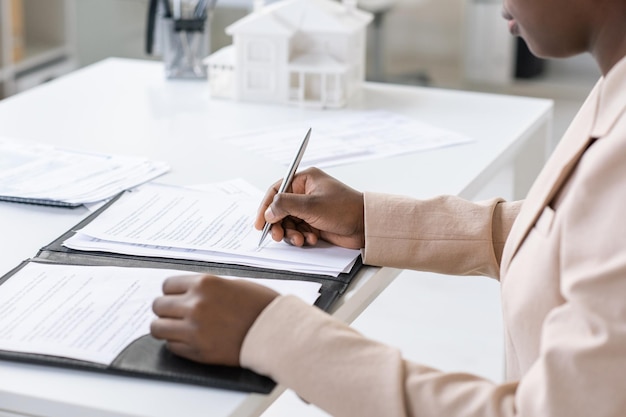 Hands of young african woman signing mortgage contract