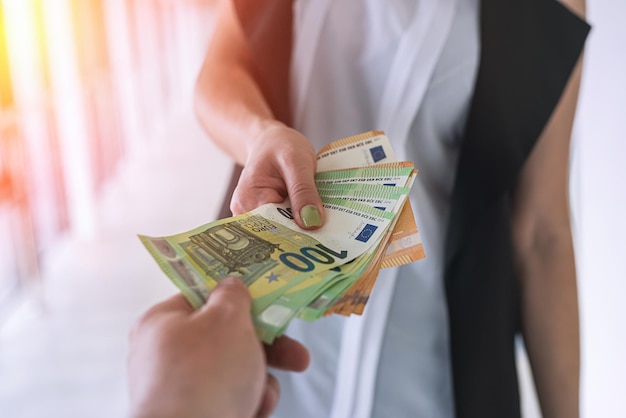 Hands of a young beautiful girl hand over a large sum of new euro bills. Business concept