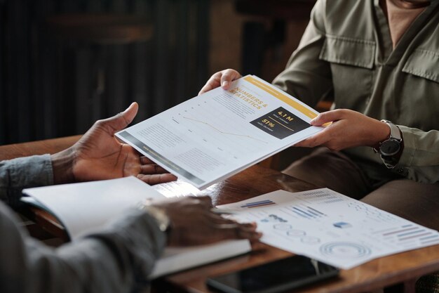 Photo hands of young businesswoman passing financial documents to colleague