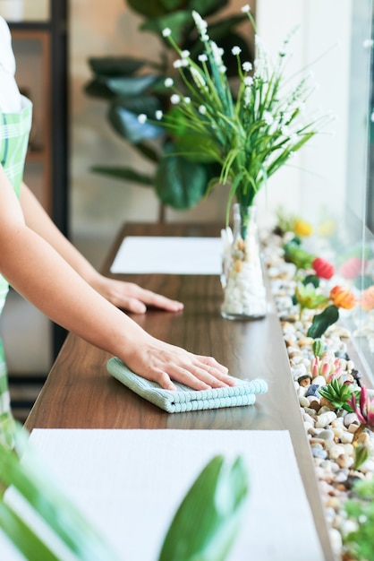 Photo hands of young coffeeshop owner wiping window sill with soft cloth