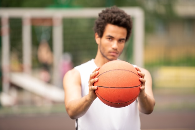 Hands of young contemporary active basketball player passing ball while holding it in front of himself