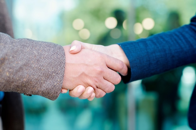 Hands of young contemporary employees in handshake symbolizing partnership, trust and unity