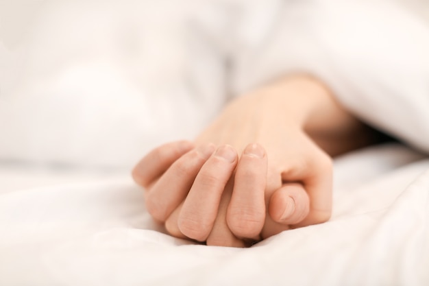 Hands of young couple sleeping in bed