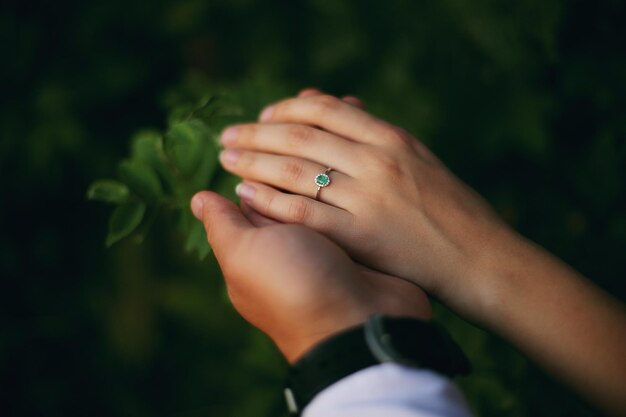 Photo hands of a young couple with a ring love couple relationship and holidays concept close up of man giving diamond ring to woman