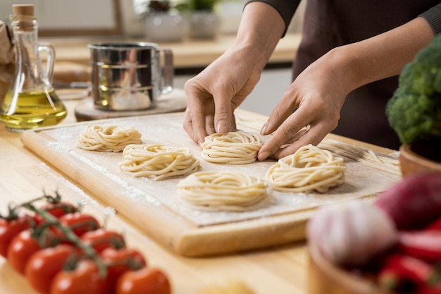 パスタを準備する若い創造的な女性の手