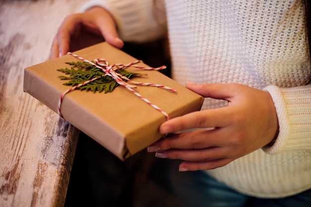 若い女の子の手がクローズアップで小さなギフトボックスを持っています。お正月やクリスマスへのプレゼント。