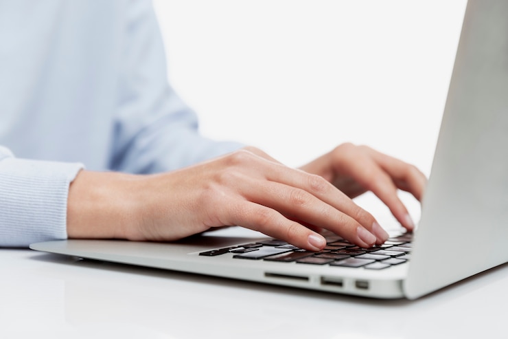 Photo hands of a young girl on a laptop keyboard. education, work and blogging. close-up. white wall.