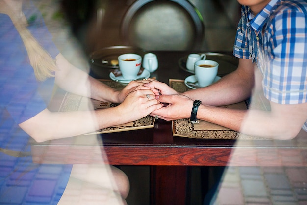 Mani di giovani amanti che tengono un caffè caldo della tazza