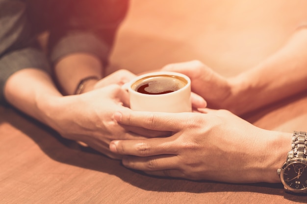 hands of young lovers holding a hot cup of coffee