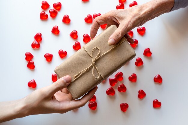 Hands of a young man give a gift to an elderly woman.