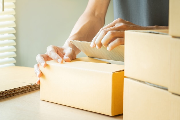 Photo hands of young man packing boxes.