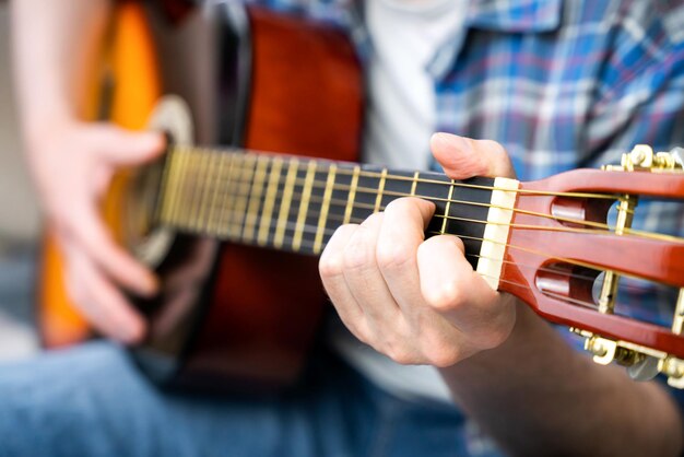 Foto mani di un giovane che suona la chitarra closeup focalizzazione selettiva