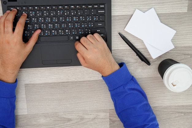 Hands of a young man typing on a laptop. the view from the top