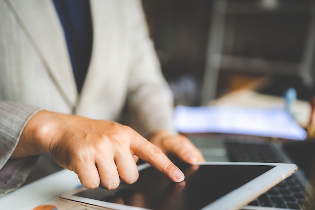 Hands of young man typing and working on digital tablet with financial and sales chart