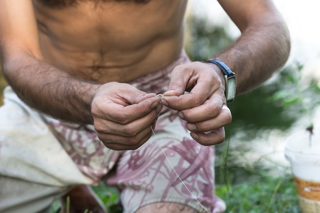 Photo hands of a young man who makes fishing gear