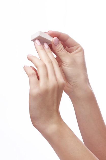 Hands of young woman holding nail file over white