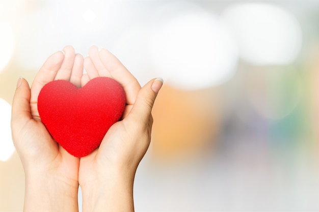 Hands of young woman holding red heart