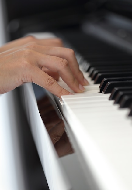 Mani di una giovane donna che suona il pianoforte