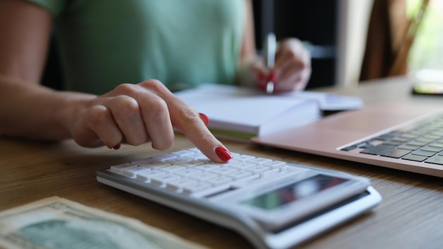 Mani della giovane donna che digitano sulla tastiera del computer e della calcolatrice digitale che preparano elettronica