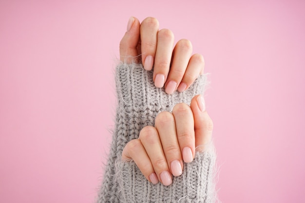 Mani di una giovane donna con bella manicure su uno sfondo rosa. manicure femminile. lay piatto, primo piano.