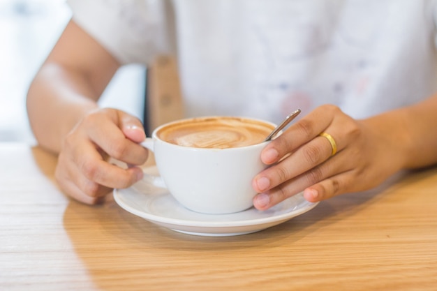 Mani della giovane donna con la tazza di cacao in polvere