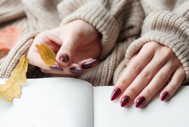 Mani di una giovane donna con manicure rosso scuro sulle unghie