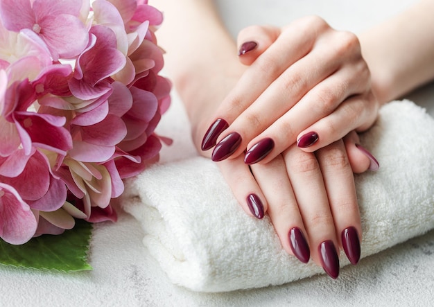 Foto mani di una giovane donna con manicure rosso scuro sulle unghie