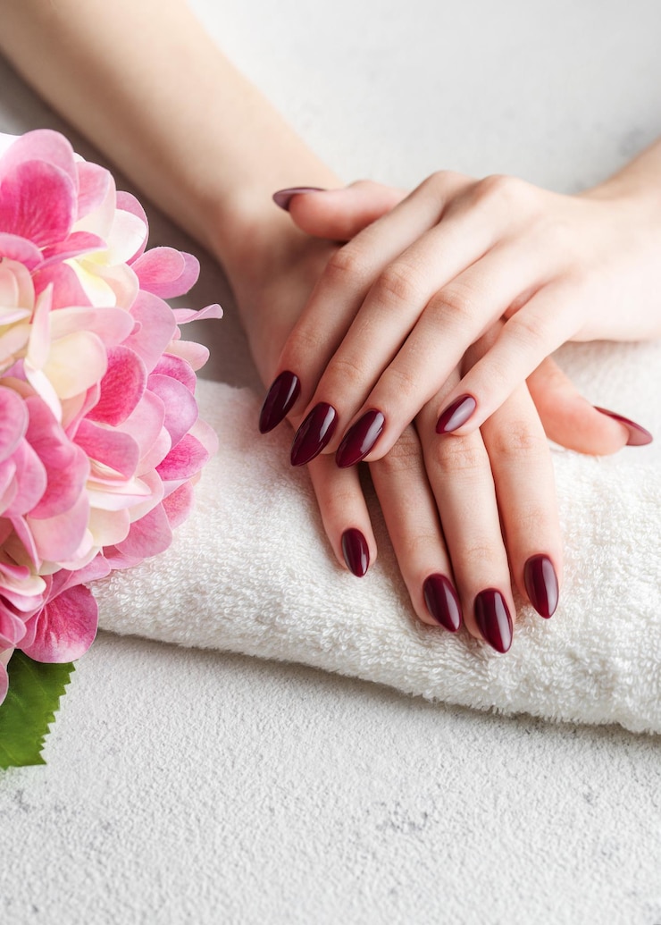 Photo hands of a young woman with dark red manicure on nails