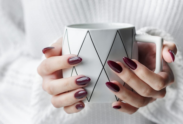 Mani di una giovane donna con il manicure bianco sulle unghie