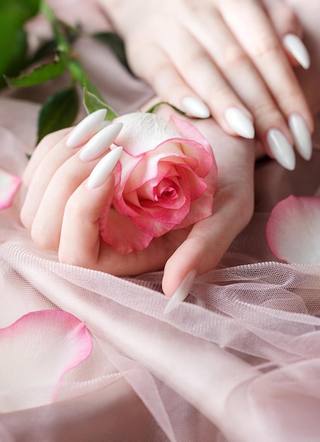 Mani di una giovane donna con il manicure bianco sulle unghie