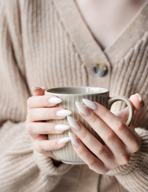 Hands of a young woman with white manicure on nails