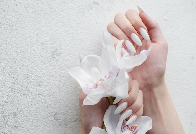 Hands of a young woman with white manicure on nails