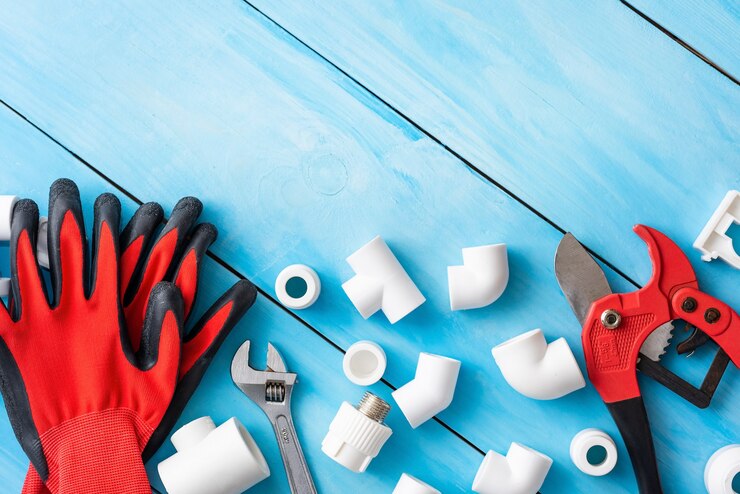 Handschoenen en pijpsnijder met plastic onderdelen voor watervoorziening.
